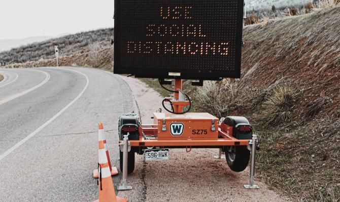 Señal móvil en una carretera con el texto luminoso "Use social distancing"