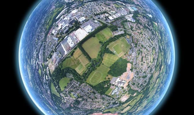A 360 panorama stitched and warped to create the tiny planet effect. Image sequence taken by drone above a community field in Wales.