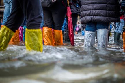 Personas caminando por una calle inundada con protecciones de plástico en los pies