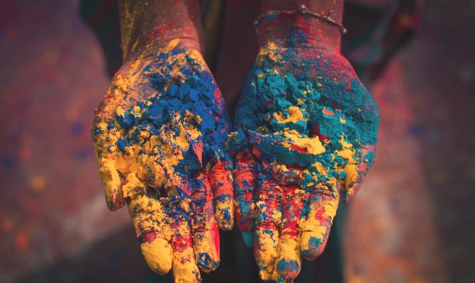 Manos mostrando pigmentos de colores en la festividad hindú de Holi, India