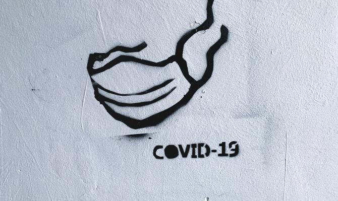 Graffiti de una mascarilla con la leyenda "COVID-19"