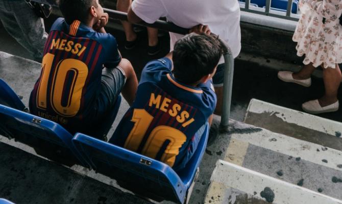 Niños con camiseta de Messi en el campo del Barça