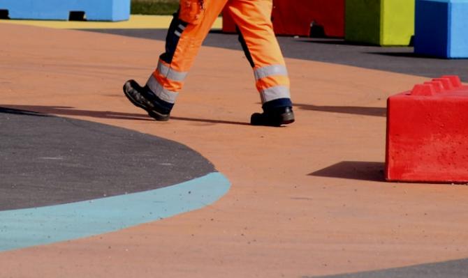 Trabajador con un mono de color naranja en un parque infantil. Photo by Anne Nygard on Unsplash