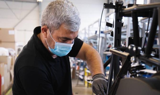 Trabajador con mascarilla manipulando maquinaria. Photo by Kumpan Electric on Unsplash