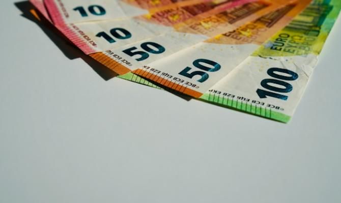 Billetes de euro dispuestos en forma de abanico sobre un fondo blanco. Photo by John Vid on Unsplash