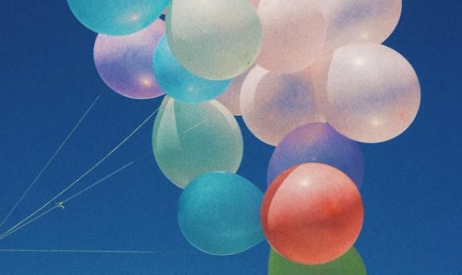 Globos de colores en cielo azul con nube. Photo by Diya Pokharel on Unsplash