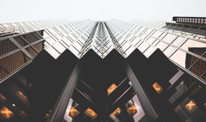 Plano contrapicado de un rascacielos de acero oscuro y vidrio. Photo by Lianhao on Unsplash