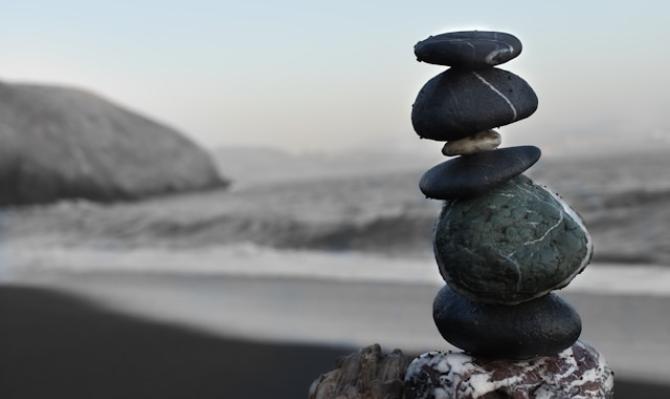 Piedras apiladas en una playa para ilustrar un artículo de opinión sobre la economía internacional de CaixaBank Research. Photo by Colton Sturgeon on Unsplash