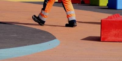 Trabajador con un mono de color naranja en un parque infantil. Photo by Anne Nygard on Unsplash