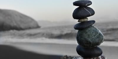 Piedras apiladas en una playa para ilustrar un artículo de opinión sobre la economía internacional de CaixaBank Research. Photo by Colton Sturgeon on Unsplash