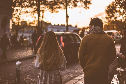 Padre e hija de espaldas paseando por una calle europea