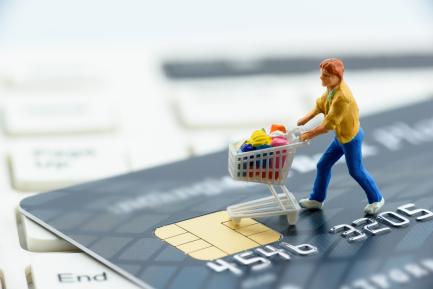 Figurita de mujer empujando un carrito de la compra sobre una tarjeta de crédito