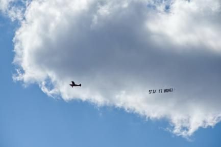 Avioneta con un cartel con el mensaje "Stay at home"