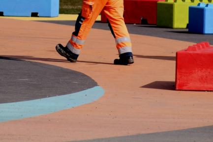 Trabajador con un mono de color naranja en un parque infantil. Photo by Anne Nygard on Unsplash