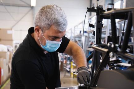 Trabajador con mascarilla manipulando maquinaria. Photo by Kumpan Electric on Unsplash