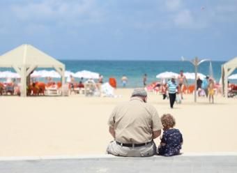 Anciano y niño en la playa. Photo by Mary Blackwey on Unsplash