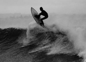 Surfista encima de una tabla sobre una ola. Photo by Alex Wigan on Unsplash