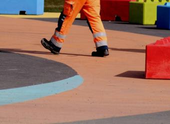 Trabajador con un mono de color naranja en un parque infantil. Photo by Anne Nygard on Unsplash