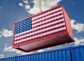 Contendor de mercancías con la bandera de Estados Unidos izado por una grua