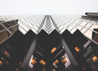 Plano contrapicado de un rascacielos de acero oscuro y vidrio. Photo by Lianhao on Unsplash