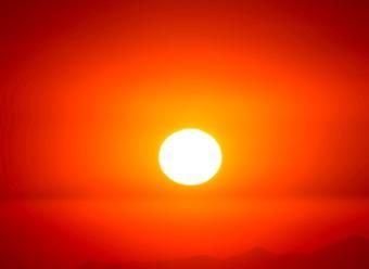 Sol ardiente sobre cielo rojo para ilustrar un artículo de CaixaBank Research sobre el impacto del cambio climático en la economía y en el turismo. Photo by Luis Graterol on Unsplash