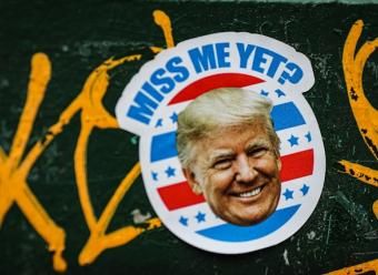 Pegatina con la cara de Donald Trump y el texto "Miss me yet" para ilustrar un artículo sobre política comercial estadounidense en el Informe Mensual 09/2026 de CaixaBank Research